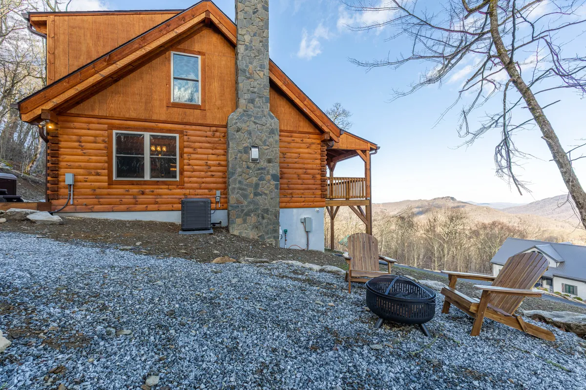 A classic log cabin set against a backdrop of mountains with a stone chimney, fire pit, and Adirondack chairs. The setting is tailored for outdoor gatherings, storytelling by the fire, and taking in panoramic views—perfect after a day’s adventure on local trails or the slopes.