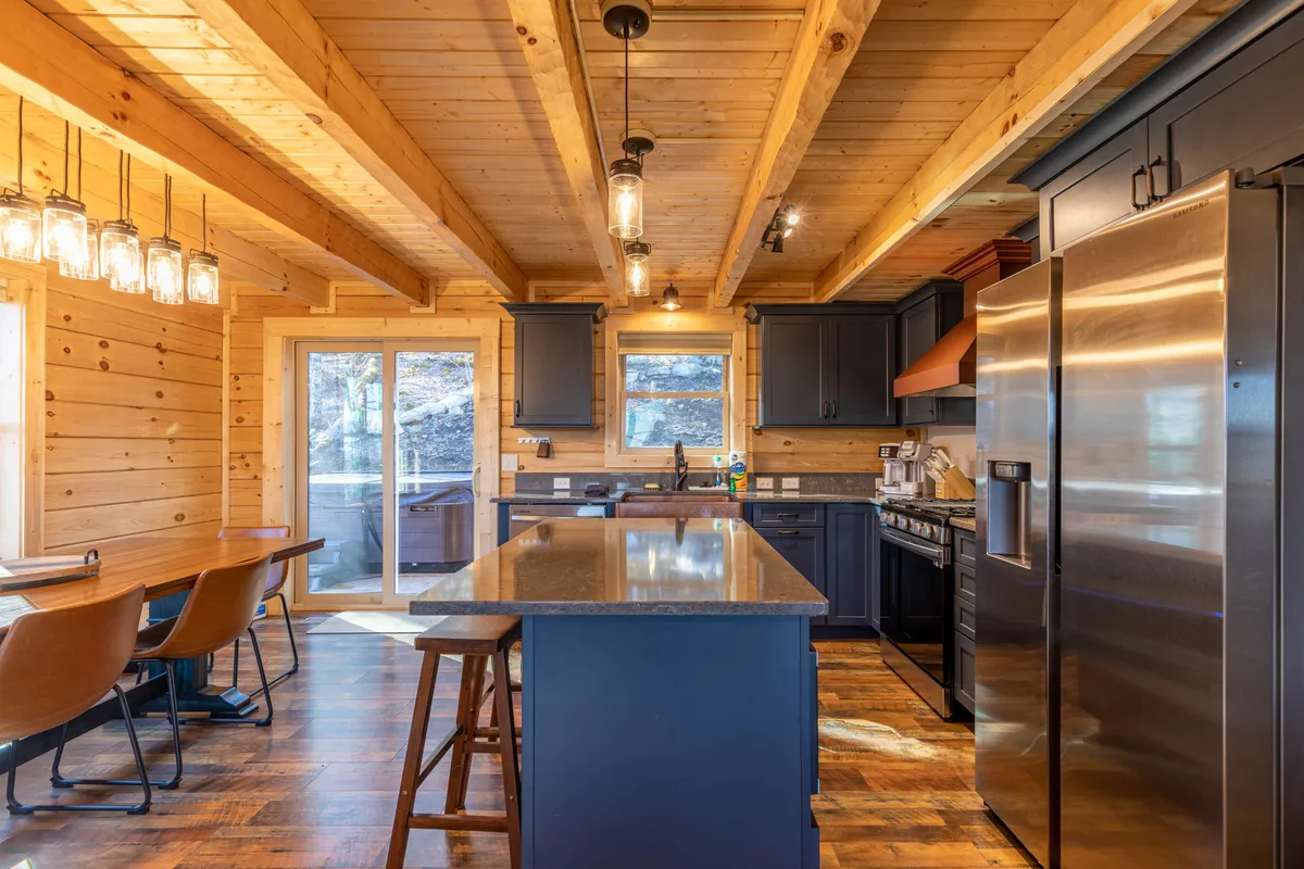 A cozy, rustic kitchen with a central island and wooden beams, blending comfort and functionality. The kitchen layout is ideal for preparing meals during an extended work stay, with natural light and a welcoming atmosphere.