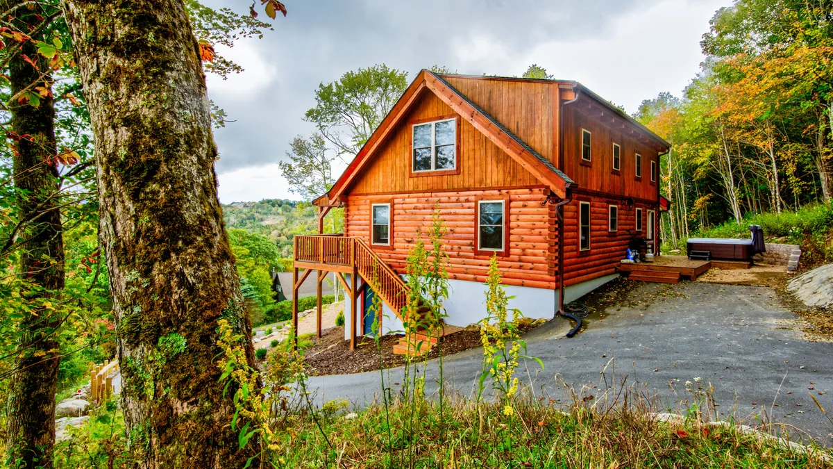 The log cabin's wooden deck is surrounded by lush greenery, inviting guests to relax or gather outdoors. The setting feels cozy yet open to nature, with plenty of space for enjoying fresh air, sunsets, or a morning coffee.